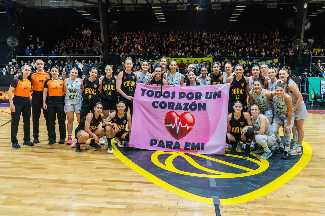 Las jugadoras de Obras Sanitarias y Ferro Carril Oeste en la previa del segundo partido de la Liga Nacional Femenina desplegaron un cartel para apoyar a Emi Troncoso. 