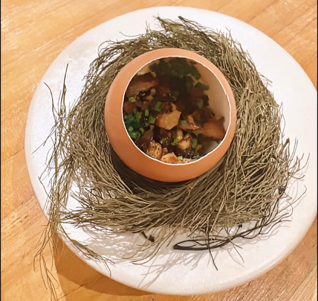 Uno de los platos del menú, bajo la pregunta: ¿Qué fue primero, el huevo o el pollo? Es una cáscara de huevo rellena de un flan de estilo japonés, hecho con caldo de pollo, ragú de pollo y ciboulette. 