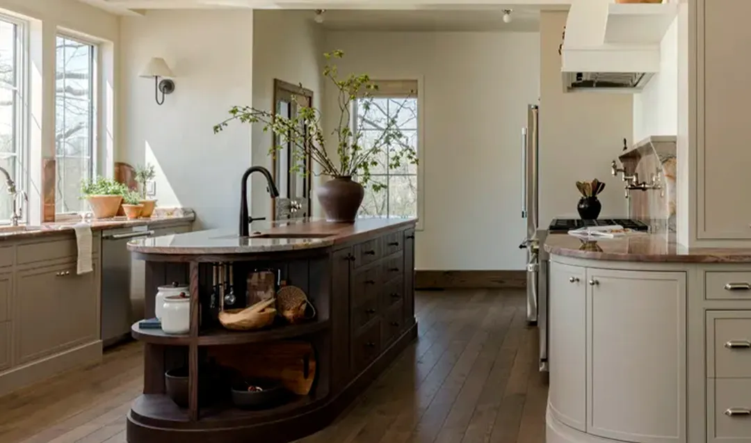 Los gabinetes pintados protagonizan esta cocina, equilibrados por una isla de madera oscura y un piso de madera media.