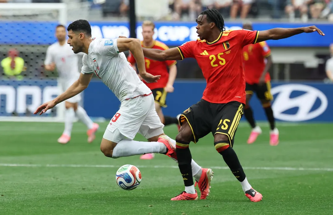 El iraní Mehdi Taremi se lleva la pelota ante la marca de Nathan Ngoy, mediocampista de Bélgica. 