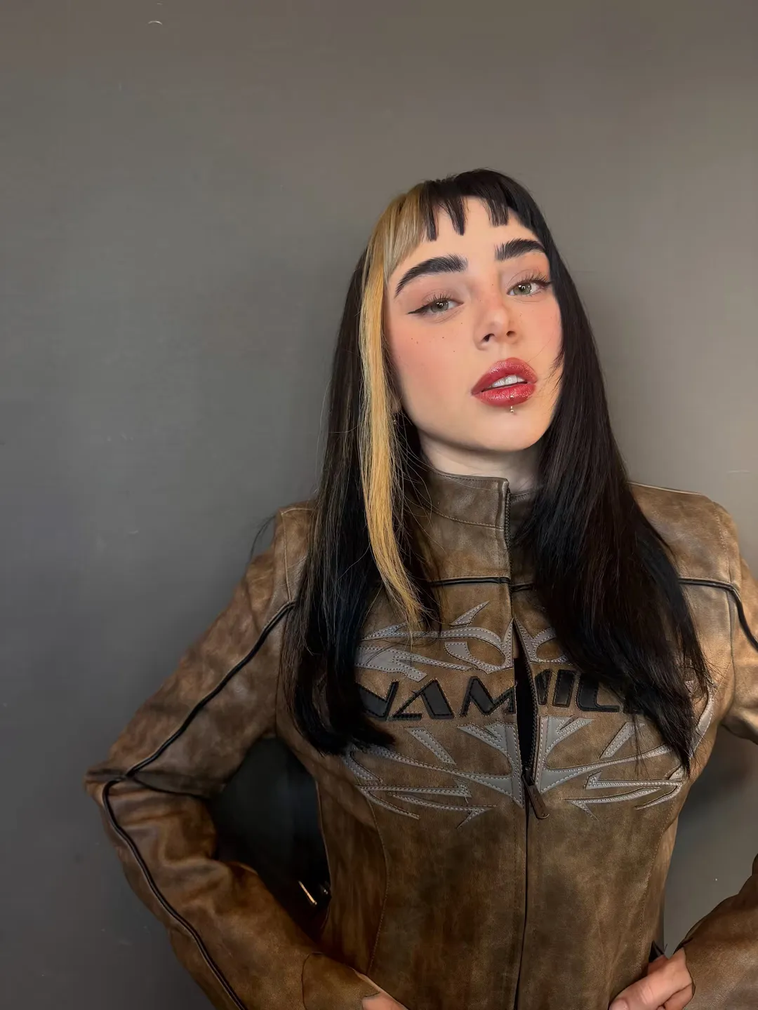 El flequillo desmechado, la mecha rubia y el make up con labios rojos brillantes.